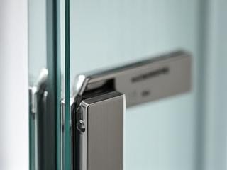 Close-up of frameless shower enclosure hinge and clear glass